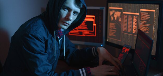 Male hacker in a hoodie attacking a database