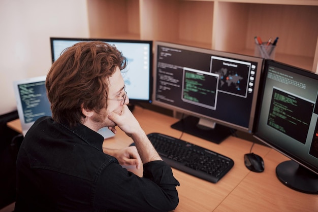 Male programmer working on desktop computer with many monitors at office in software develop company Website design programming and coding technologies