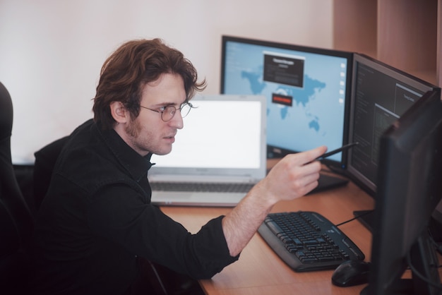Male programmer working on desktop computer with many monitors at office in software develop company. Website design programming and coding technologies