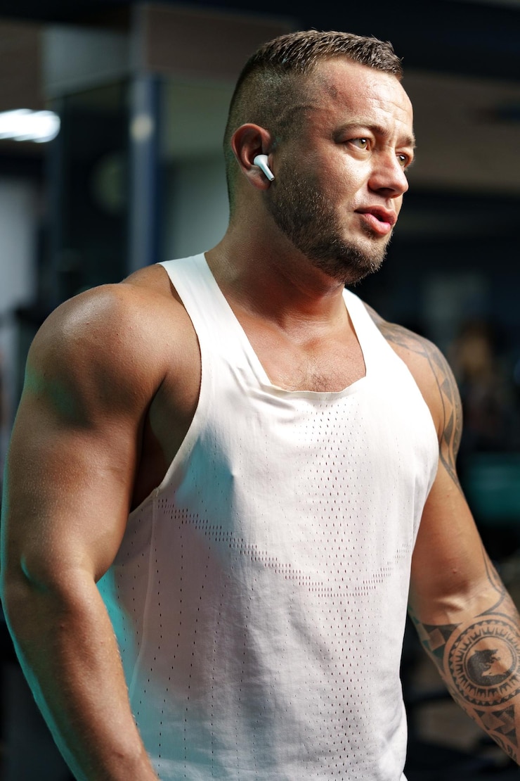 Fotografie man bodybuilder in white shirt training in a gym
