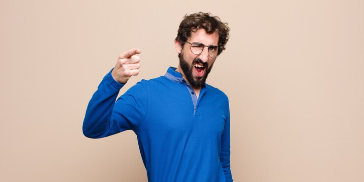 Fotografie man pointing with an angry aggressive expression looking like a furious, crazy boss