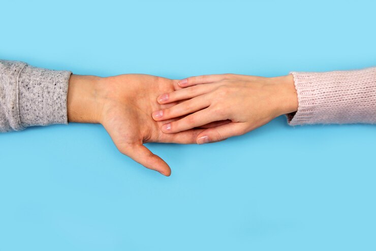 Fotografie man's and woman's hands keep box with wedding ring on blue.