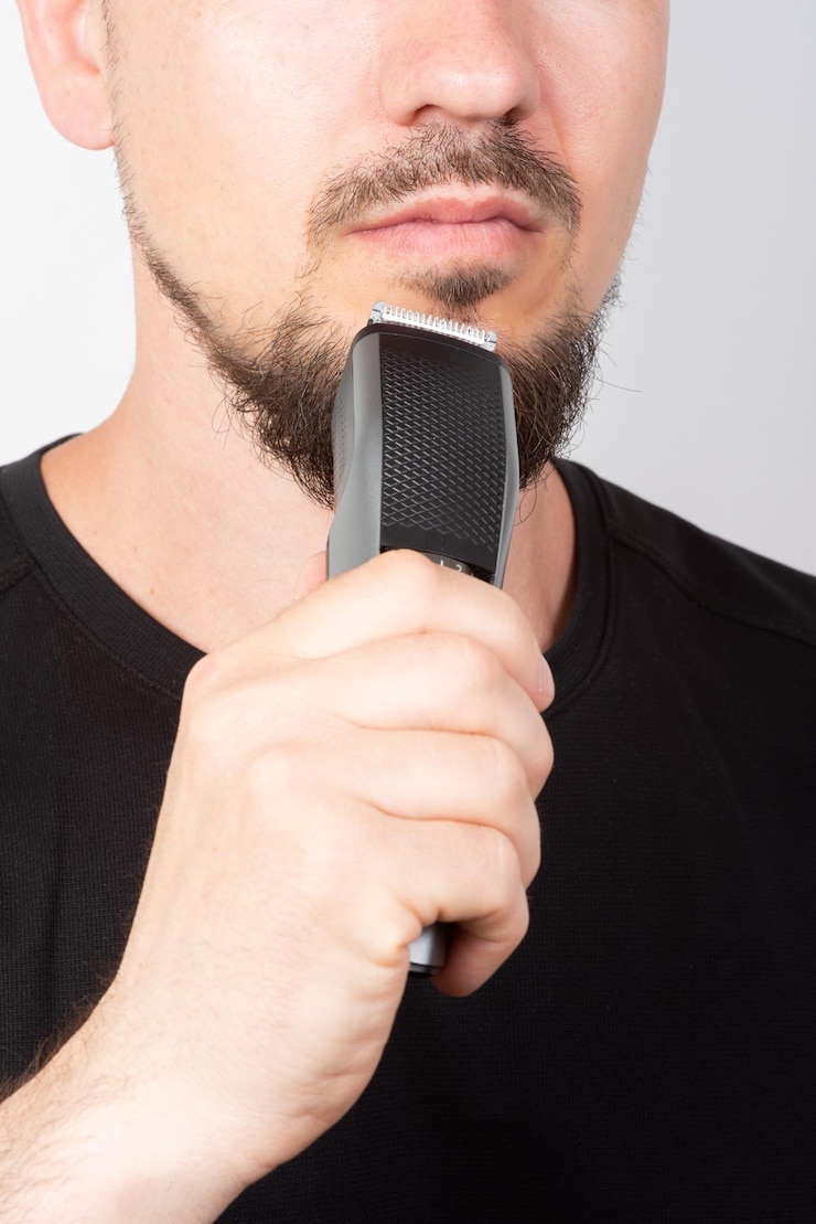 Fotografie man shaving his beard with a trimmer closeup