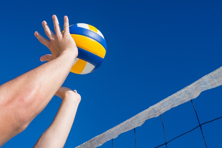 Fotografie man throwing volleyball above the net