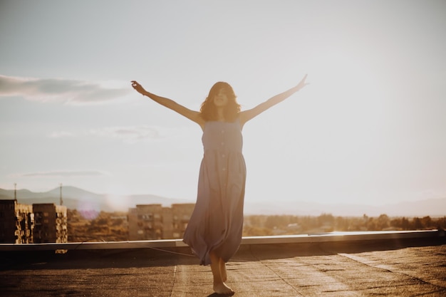 Mature woman standing with arms outstretched on terrace during sunset