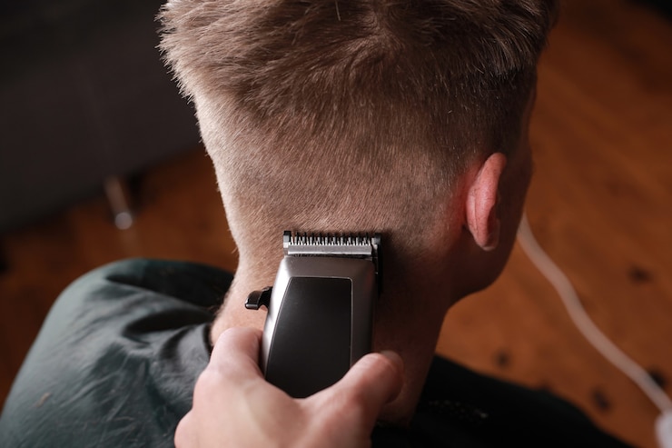 Fotografie men's haircut, the master cuts the guy with a hair clipper, hairdressing tool.
