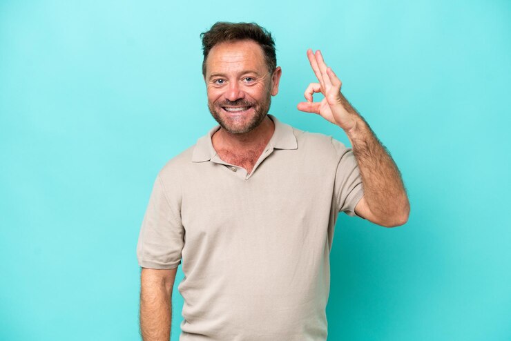 Fotografie middle age caucasian man isolated on blue background showing ok sign with fingers