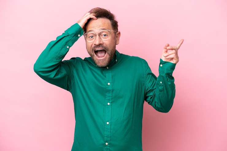 Fotografie middle age caucasian man isolated on pink background surprised and pointing finger to the side