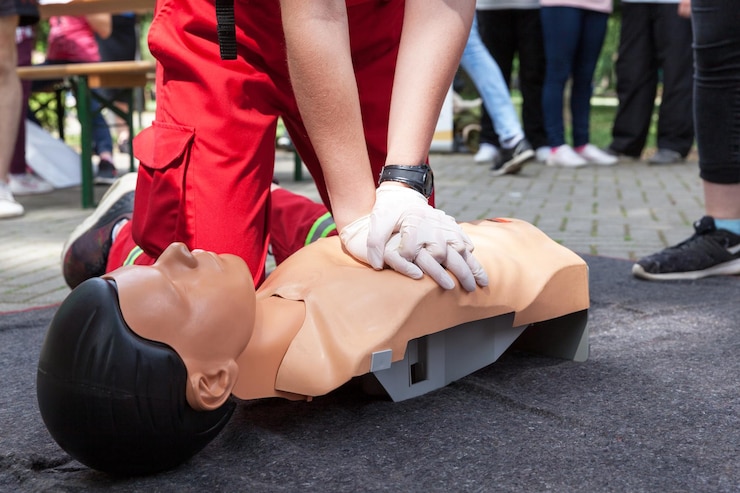 Fotografie midsection of instructor teaching paramedic while performing cpr on dummy on footpath in city