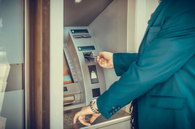 Midsection of man inserting card in atm machine