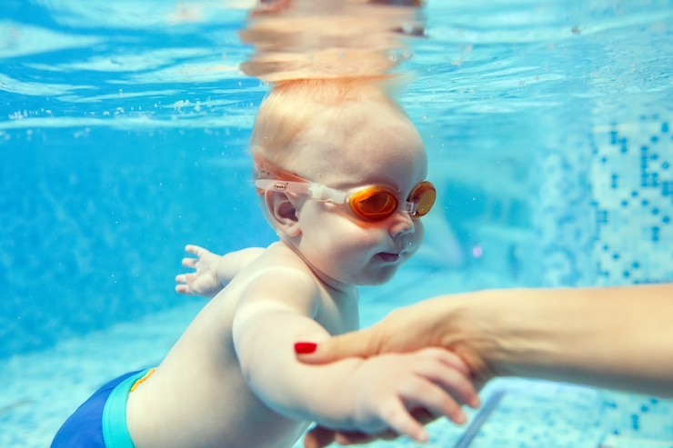 Fotografie mom teaches a child to swim in the pool