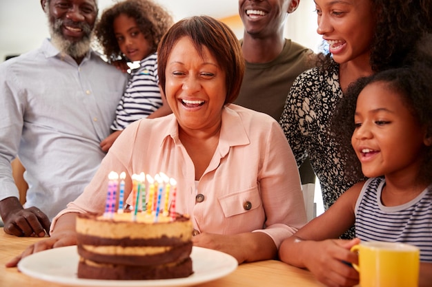 multigeneration family celebrating grandmothers birthday at home with cake and candles