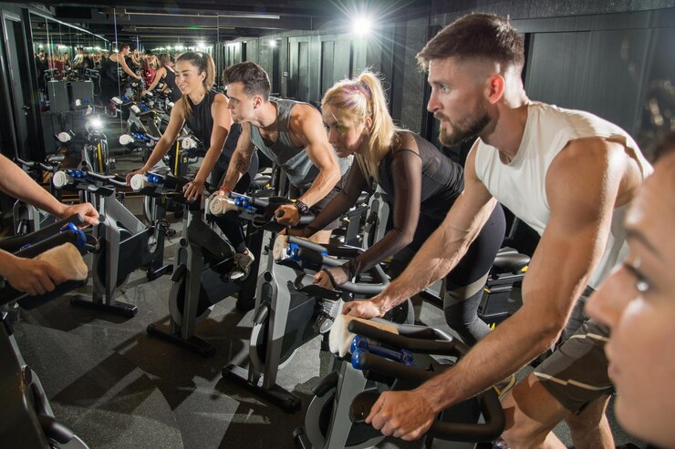Fotografie muscular young men and women on cycling class at gym