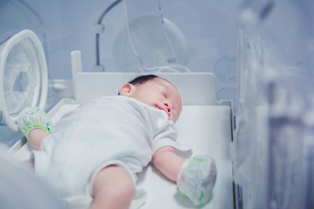 newborn baby boy covered in vertix inside incubator.