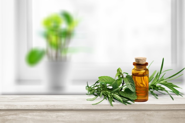 Oil bottle and green herbs on blue background