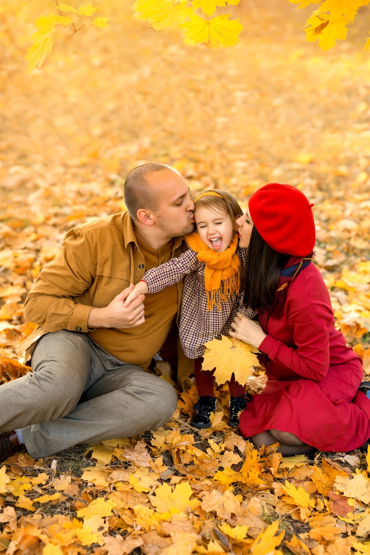 Fotografie parents kiss their twoyearold daughter on the cheek sitting on the dry yellow leaves