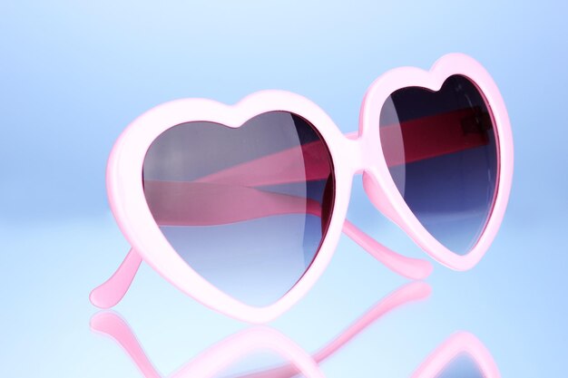 pink heartshaped sunglasses on blue background