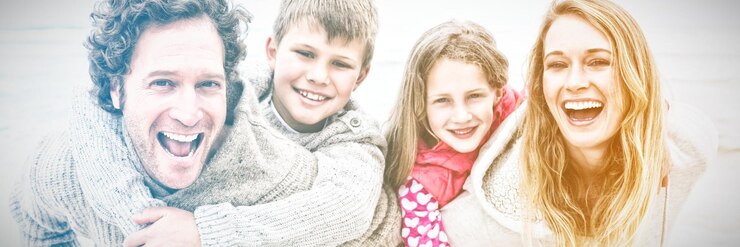 Fotografie portrait of a happy couple piggybacking their kids at the beach