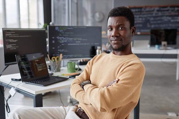Portrait of African American programmer looking at camera while sitting in IT office
