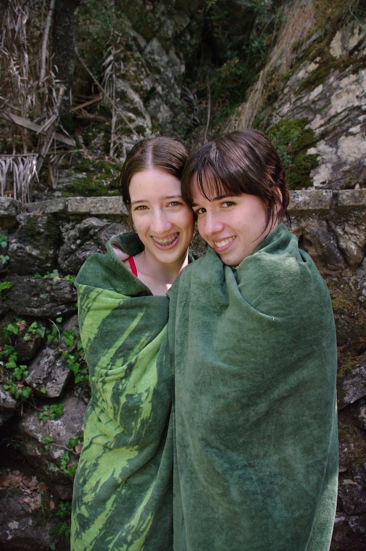 Fotografie portrait of female friends wrapped in green towel against rock formations