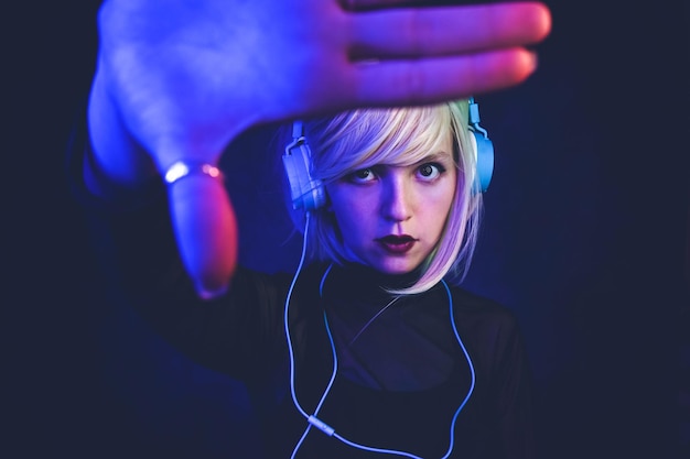 portrait of mid adult woman listening music against black background