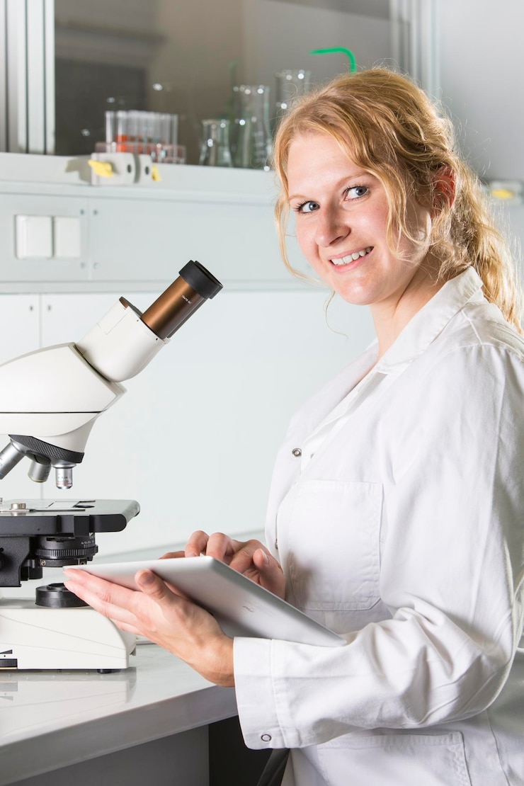 Fotografie portrait of smiling woman using digital tablet by microscope on table in laboratory