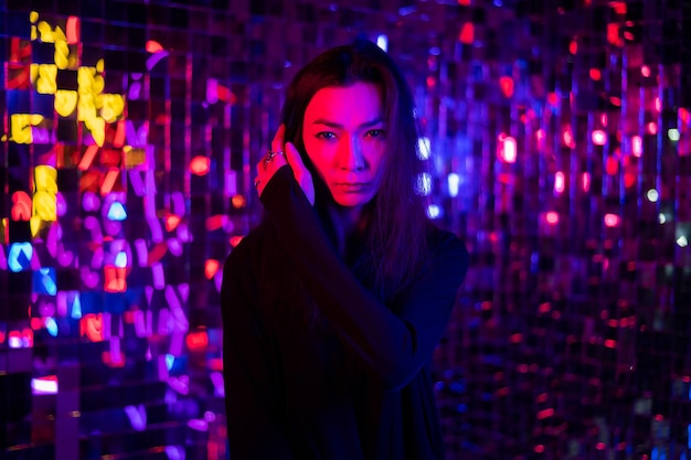 portrait of young woman standing against illuminated christmas tree