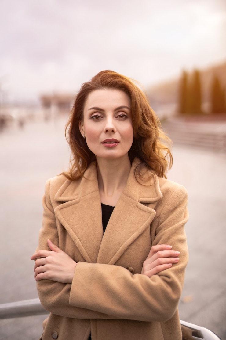 Fotografie pretty parisian woman in an autumn beige coat beautiful hair standing outdoors posing for camera