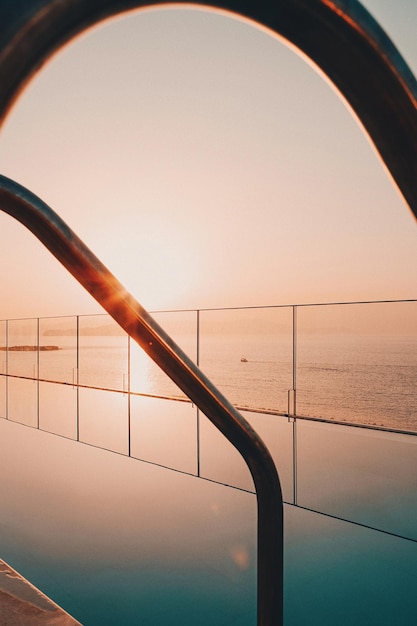 railing by pool against clear sky during sunset