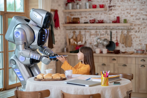 robot teacher looking attentively how the girl writing