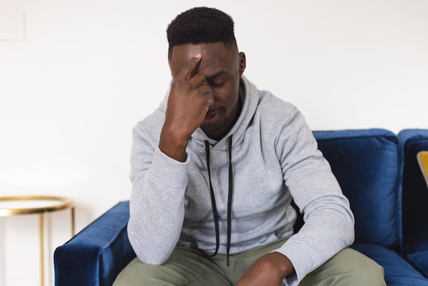 sad african american man sitting in armchair having video call at home