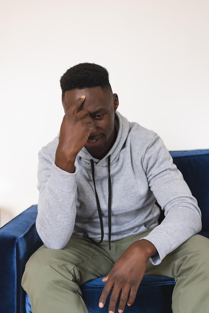 sad african american man sitting in armchair having video call at home