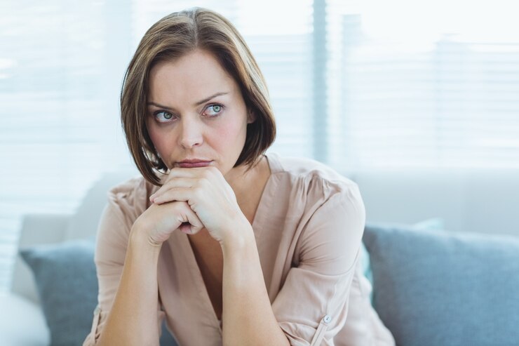 Fotografie sad woman sitting on sofa