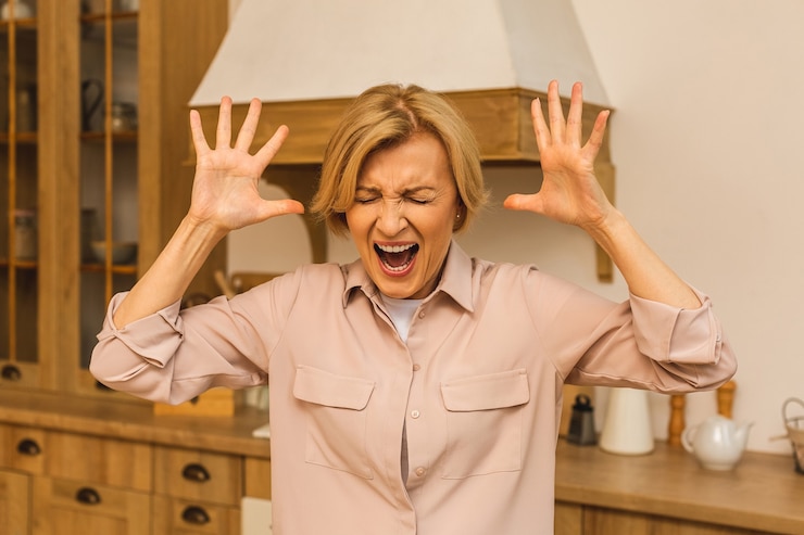 Fotografie senior mature aged woman suffering from depression on kitchen at home, domestic stress.