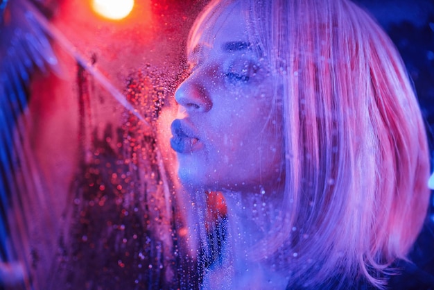 Sensual look Stylish woman with white hair is behind wet transparent plastic sheet