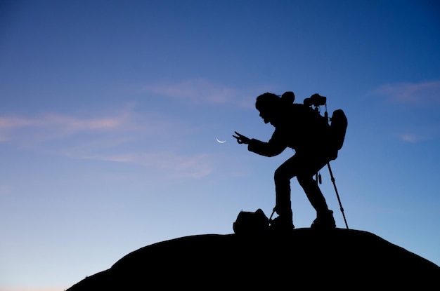 side view of a silhouette photographer against blue sky