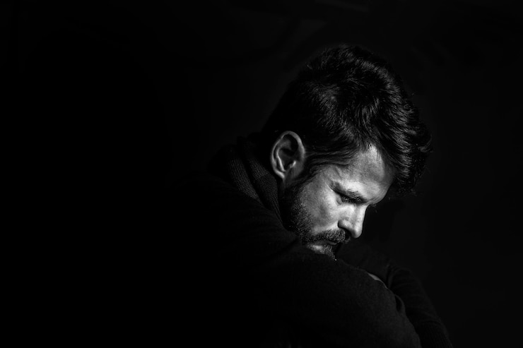 Fotografie side view of mid adult man sitting against black background
