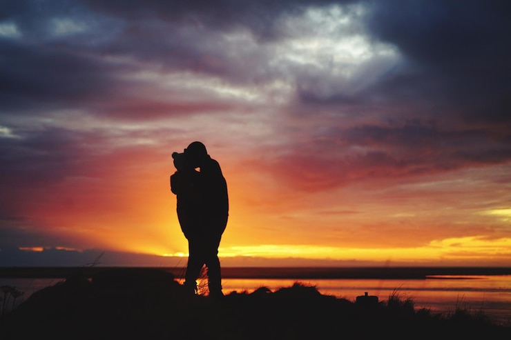Fotografie silhouette couple kissing at beach against sky during sunset