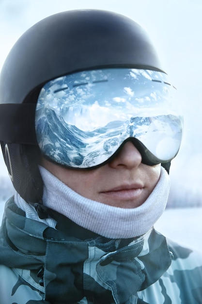 Ski goggles with the reflection of snowed mountains Man on the background blue sky Winter Sports