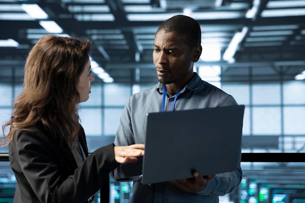 system administrators in data center using laptop analyzing metrics