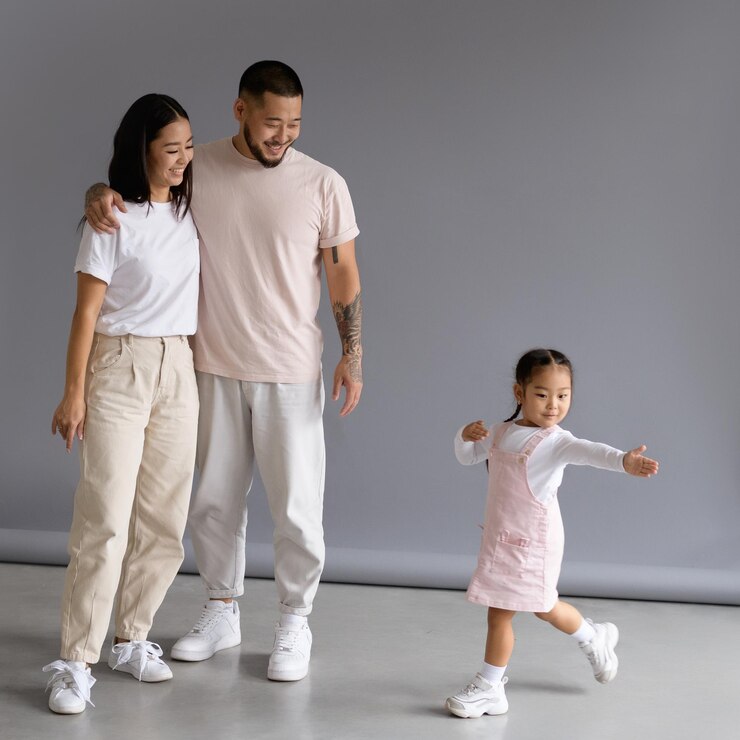 Fotografie tattooed asian man hugging wife near toddler daughter dancing on grey background