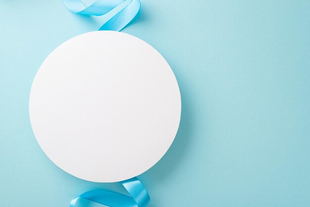 Top view photo of white empty circle with a pastel blue ribbon on an isolated light background with copyspace