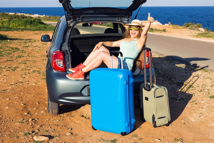 Fotografie travel, summer holidays and vacation concept - young woman with suitcases on car trip. she is sitting in car back and gesture thumbs up.