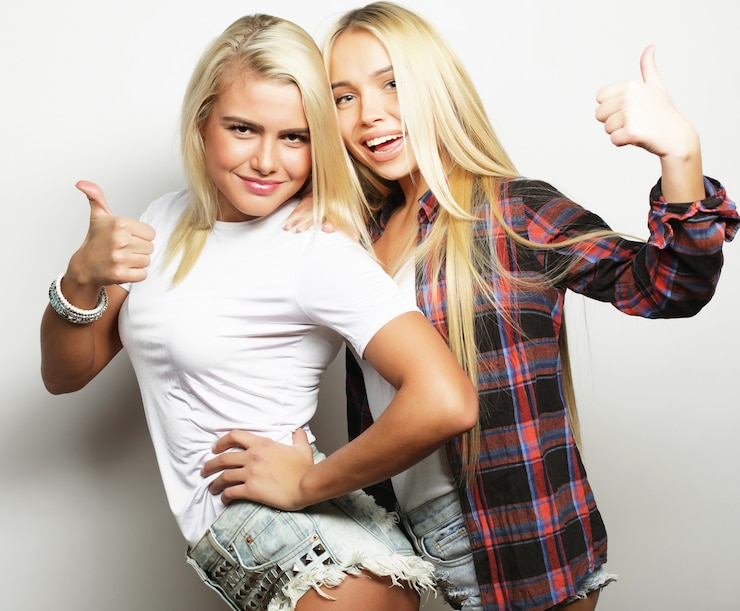 Fotografie two young girl friends standing together and having fun. looking at camera.