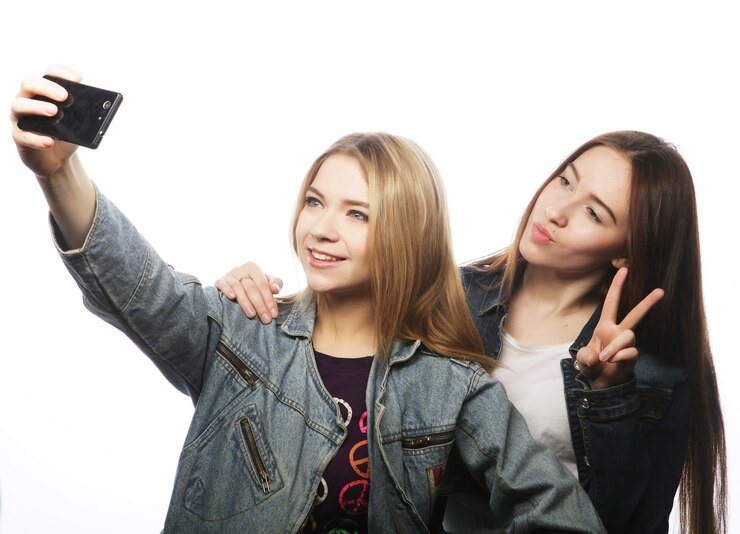 Fotografie two young women taking selfie with mobile phone, isolated on white