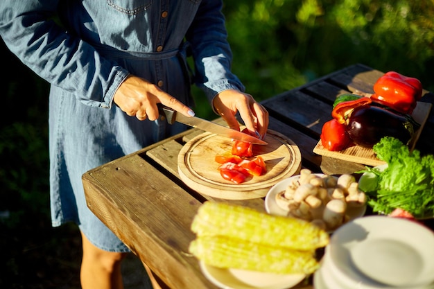 Unrecognizable woman cutting fresh pepper vegetables on wooden board