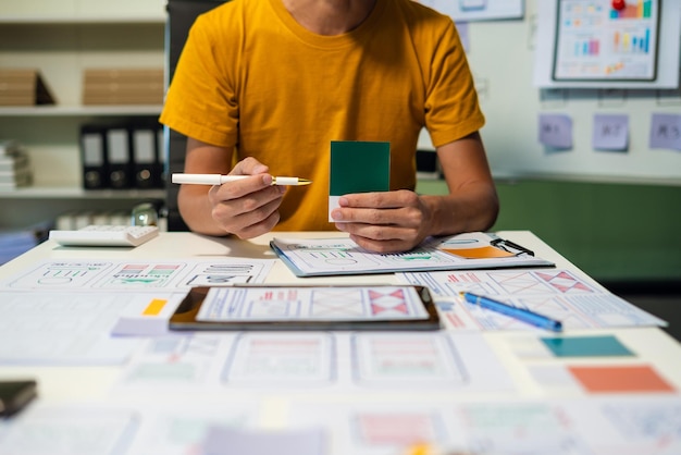 UX developer and ui designer brainstorming about mobile app interface wireframe design with customer breif and color code at office