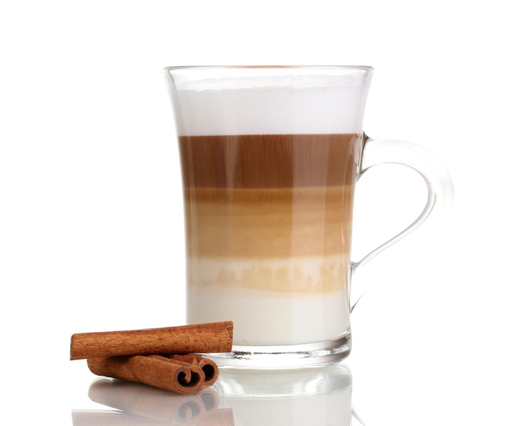Fotografie voňavé sappuccino latte ve skleněném šálku a skořice izolované na bílém pozadí