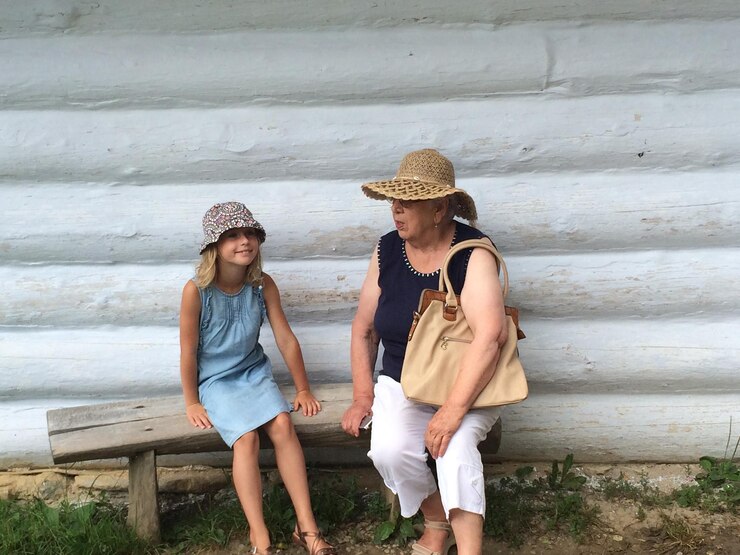 Fotografie woman and girl sitting on seat against wall