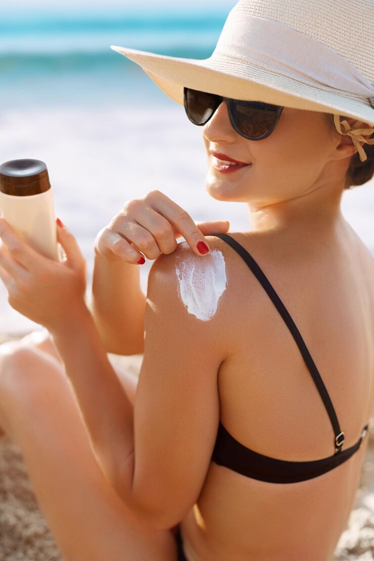 Fotografie woman applying sun cream creme on tanned shoulder sun protectionsun cream skin and body care